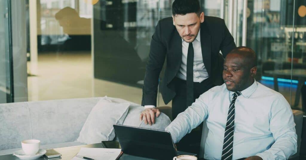 Two business professionals review candidate information together on a laptop, reflecting the consultative partnership of a retained executive search engagement.