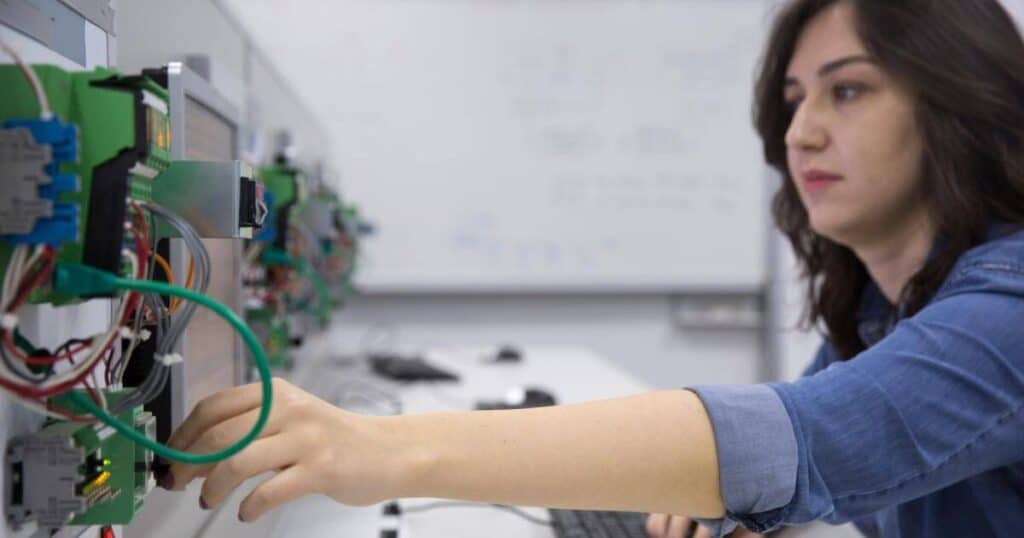 a female electrical engineer connecting cables on an automation control panel