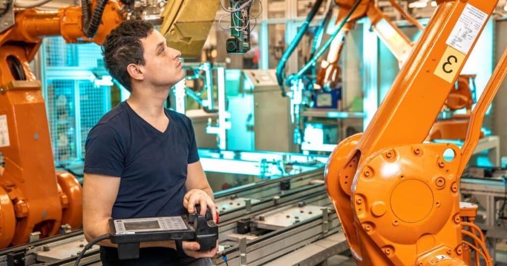 engineer programming robotic arm assembly line